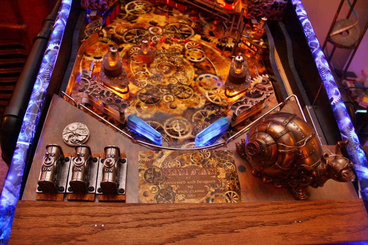 Steampunk-themed pinball machine with gears, switches, and metallic design