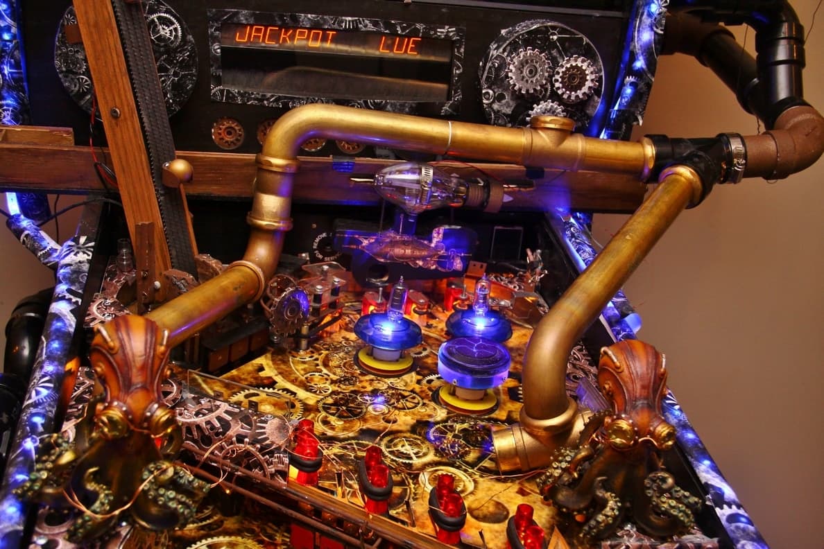 Steampunk pinball machine with golden pipes, gears, and blue-lit components