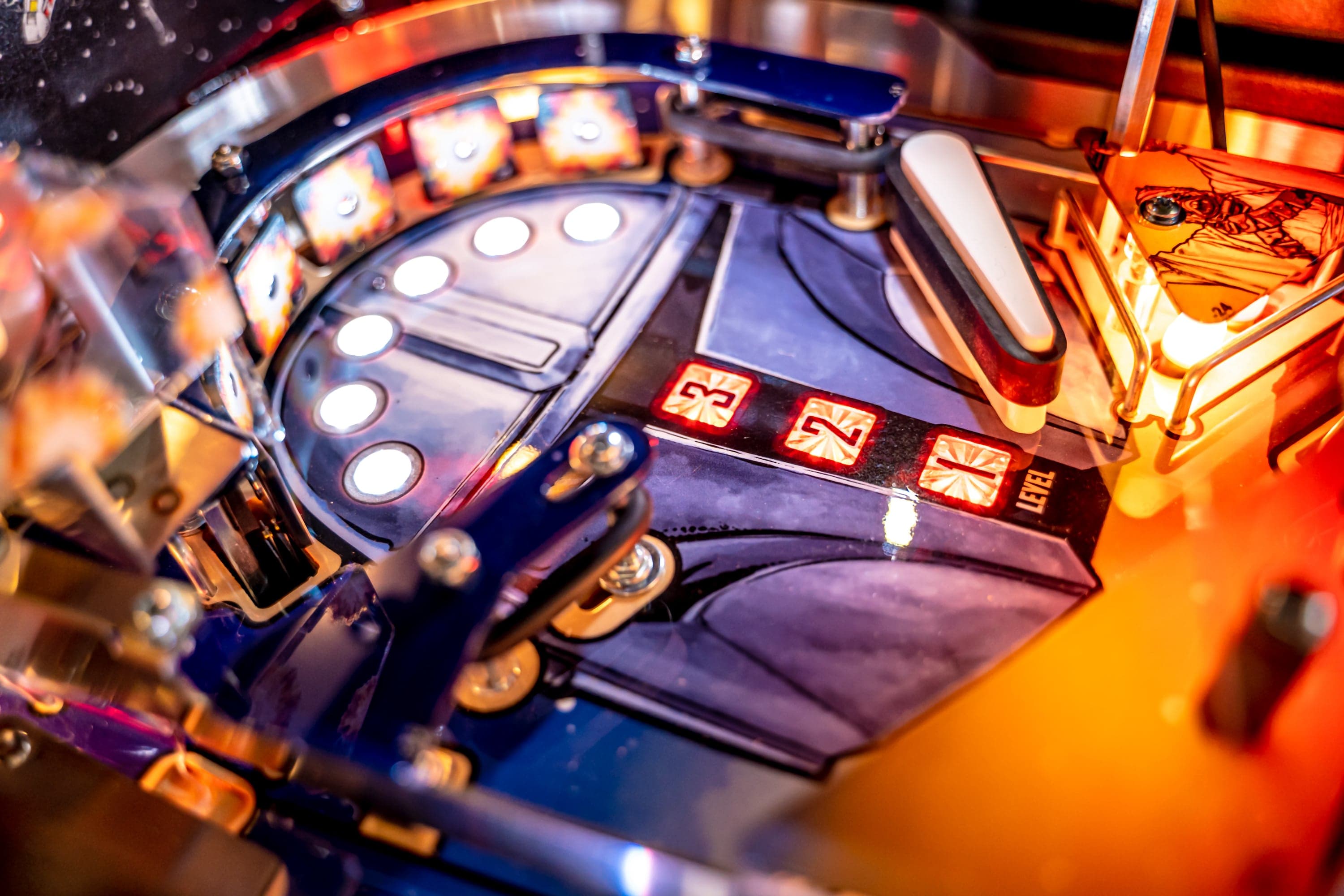 Close-up of a pinball machine with illuminated buttons and colorful lights