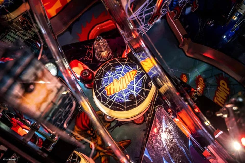 Close-up of Spider-Man themed pinball machine with vibrant colors and web design