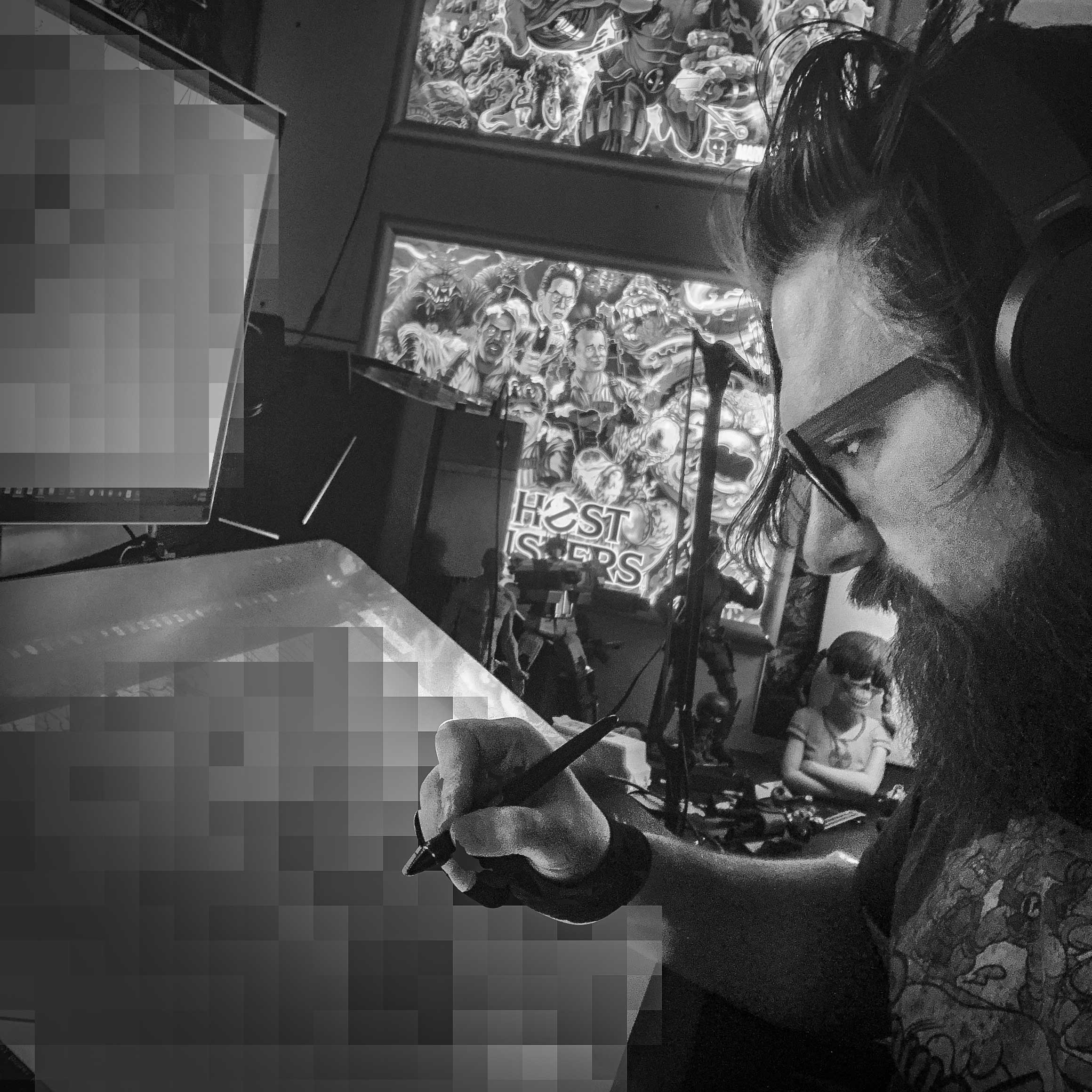 Artist drawing with Ghostbusters poster in background, black and white