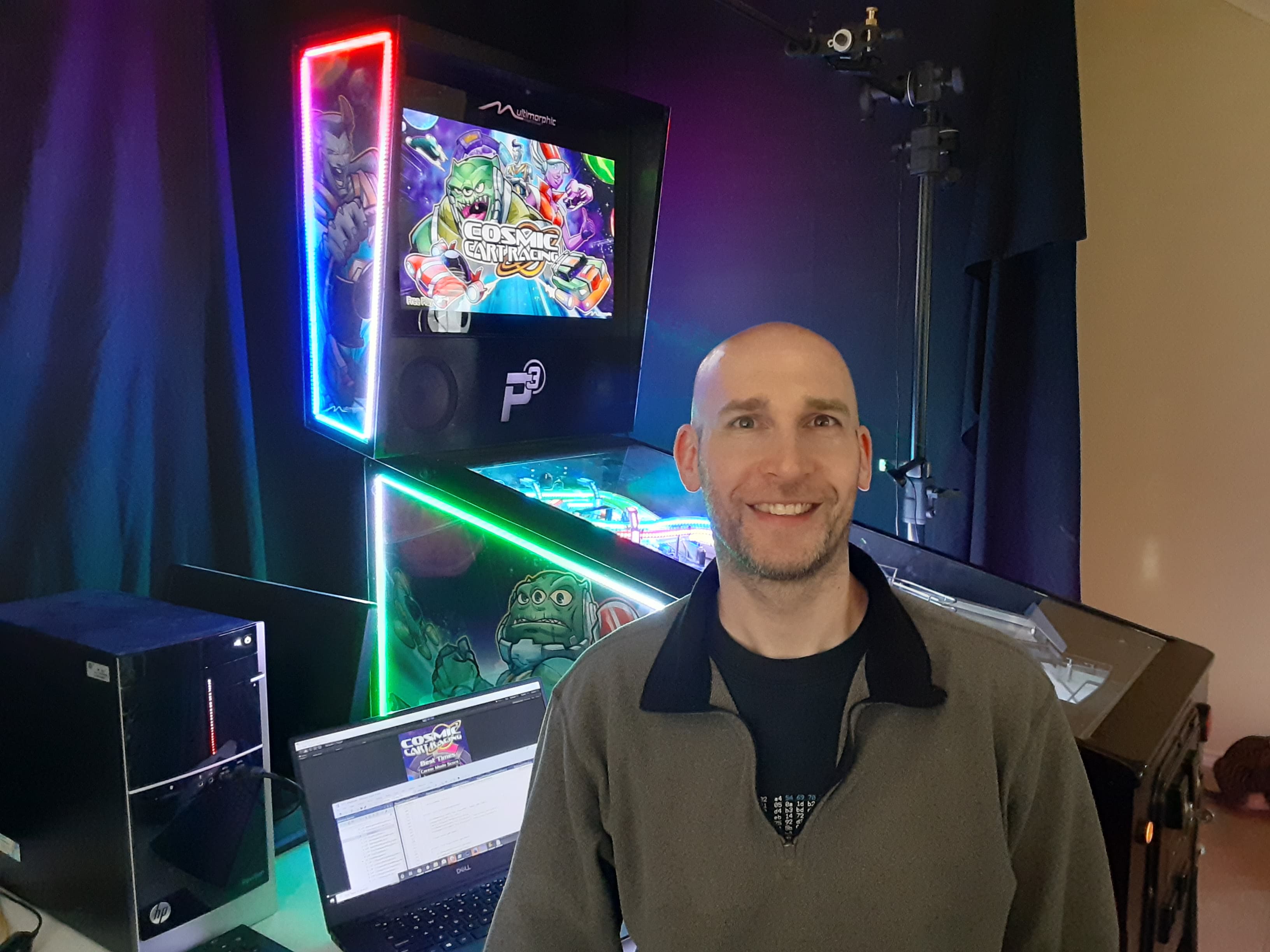 Smiling person in gaming setup with colorful screens and RGB lighting
