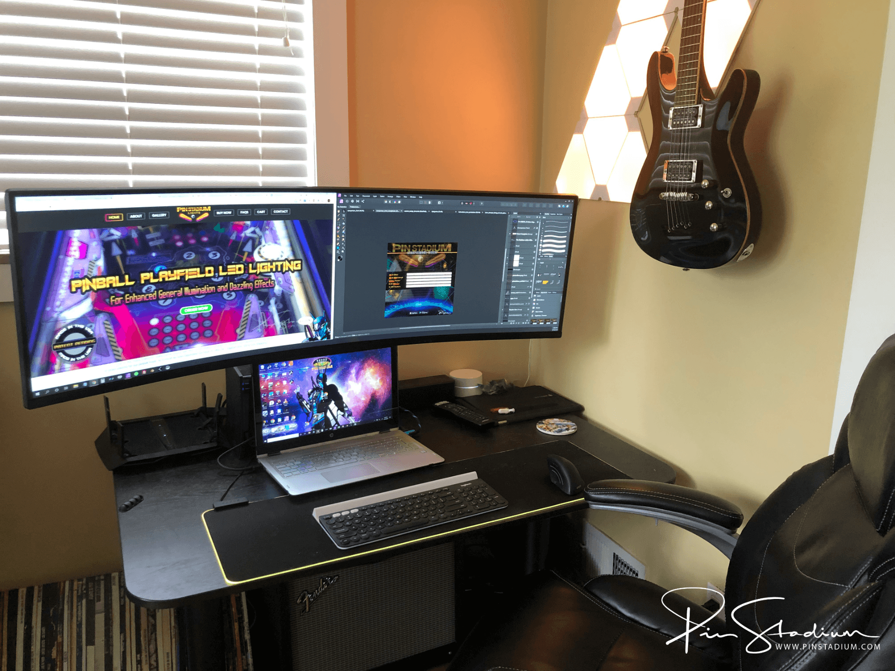 Music and gaming setup with dual monitors, laptop, and electric guitar