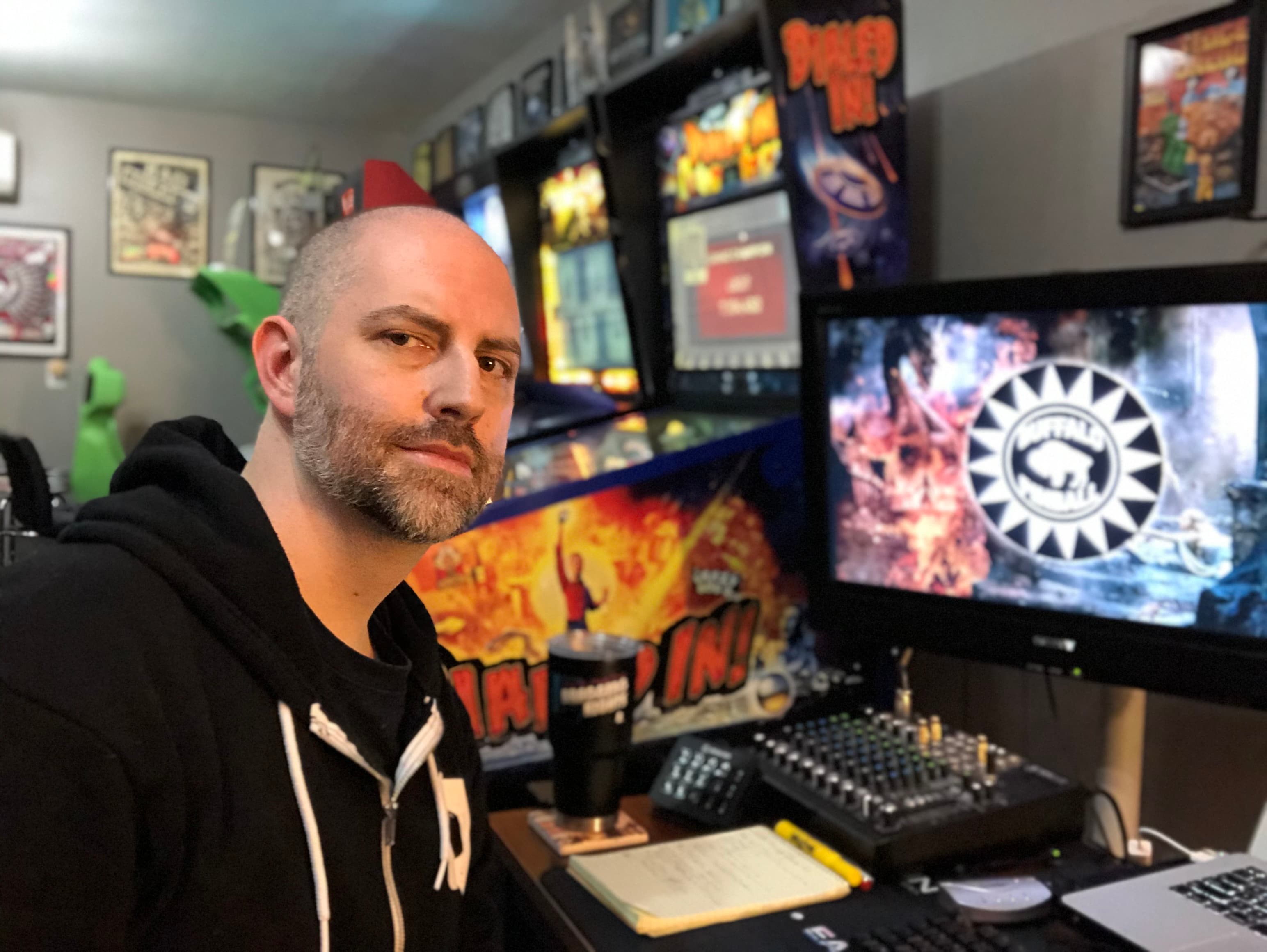 Game developer in home studio with multiple screens and gaming posters
