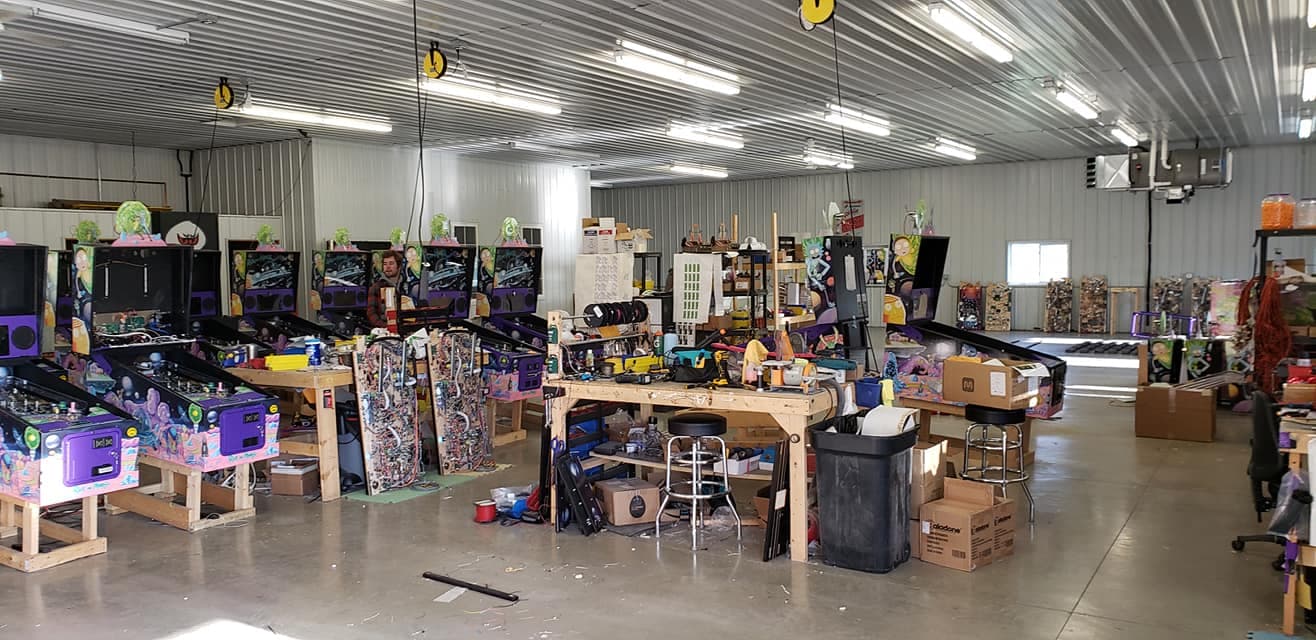 Pinball machine workshop with multiple colorful machines and workbenches