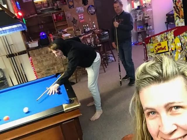 People playing pool in a colorful bar with pool table and billiard cues