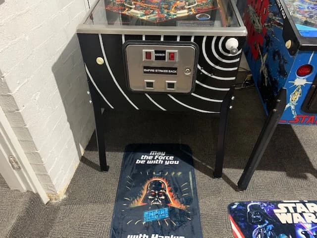 Star Wars pinball machine with Darth Vader floor mat in arcade