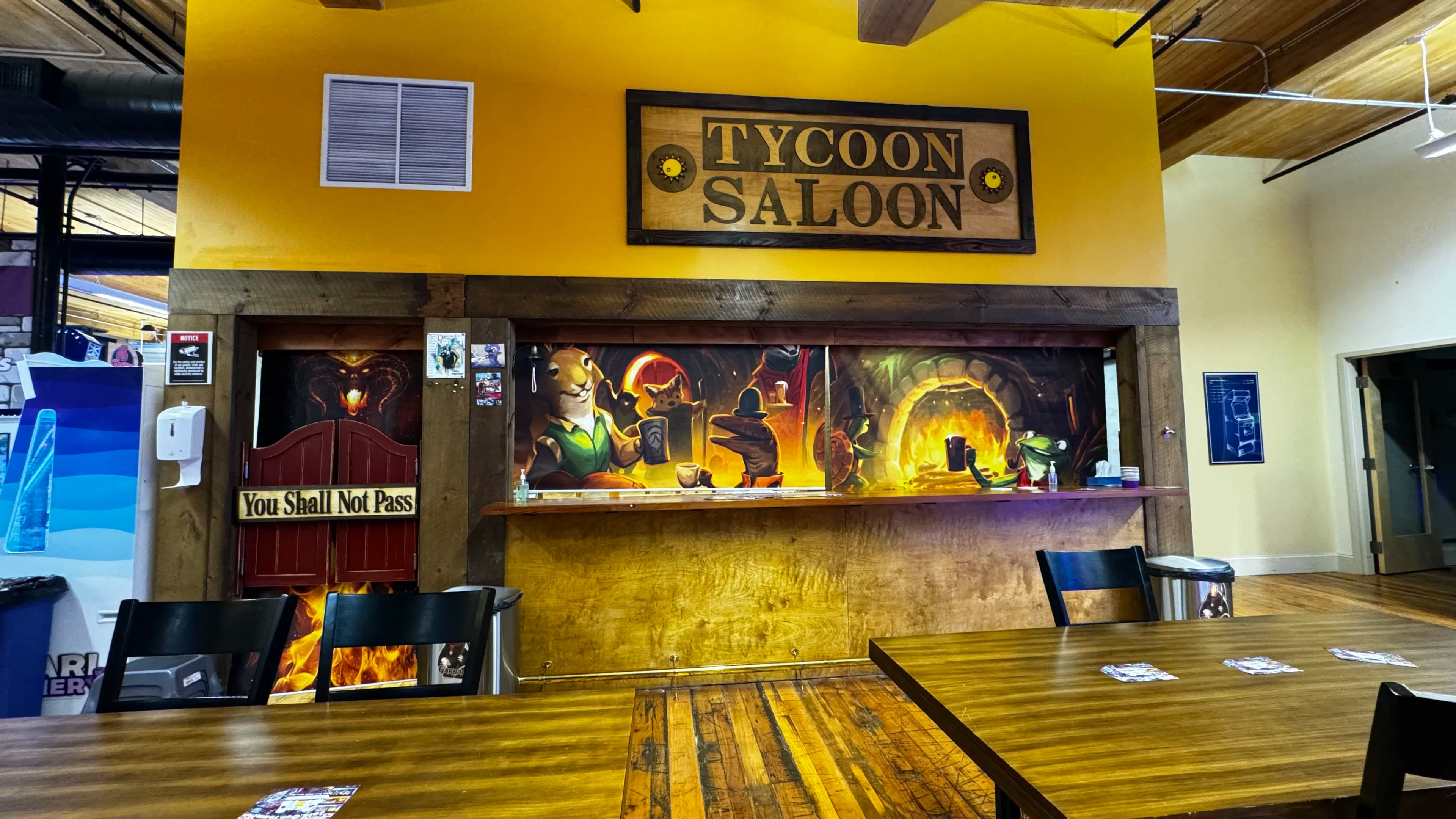 Tycoon Saloon interior with fantasy-themed wall art and wooden tables