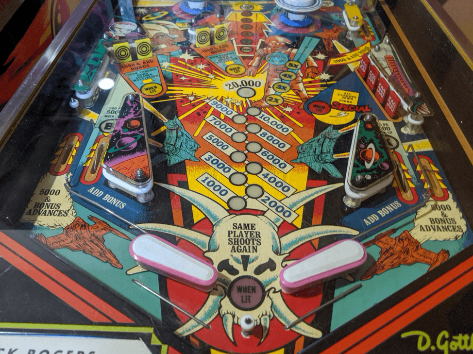 Colorful vintage pinball machine playfield with scoring zones and flippers