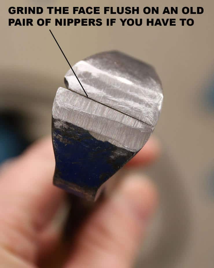 Close-up of worn metal nippers with grinding instruction text