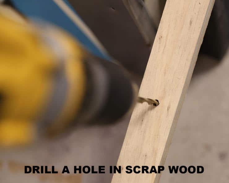 Close-up of drill creating hole in light wooden board