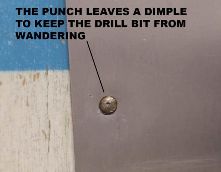 Metal punch creates dimple to guide drill bit on surface