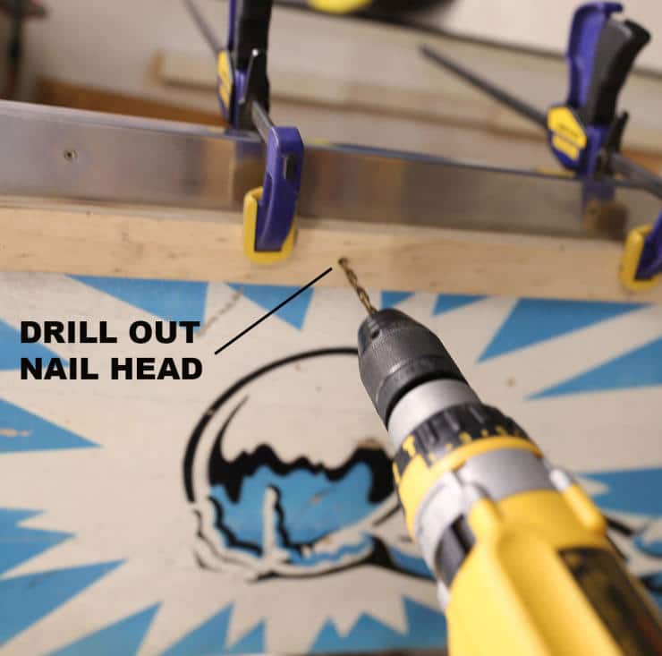 Yellow drill preparing to remove a nail head on blue and white background