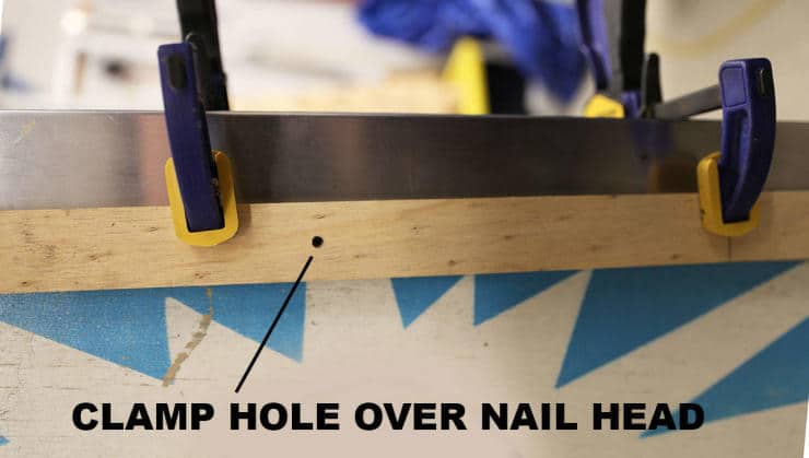 Blue woodworking clamps holding wooden board with instructional text