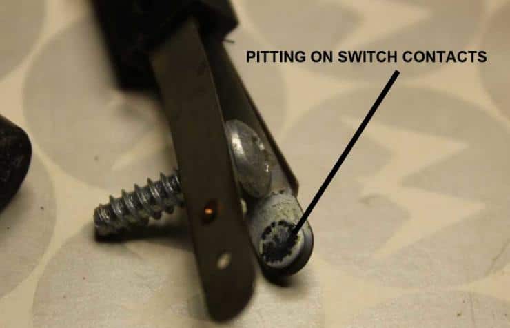 Metal screws and switch contacts showing pitting damage close-up