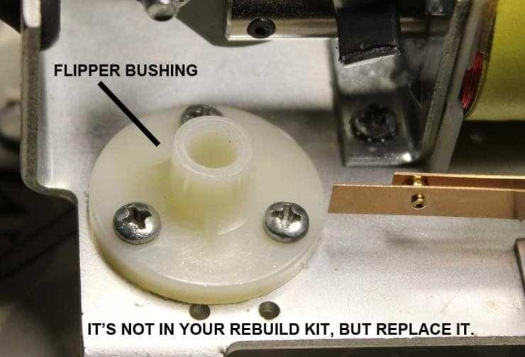 White plastic flipper bushing with mounting screws in mechanical assembly