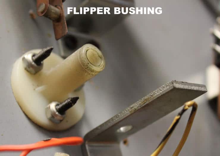 Closeup of a white flipper bushing with mounting screws and metal component