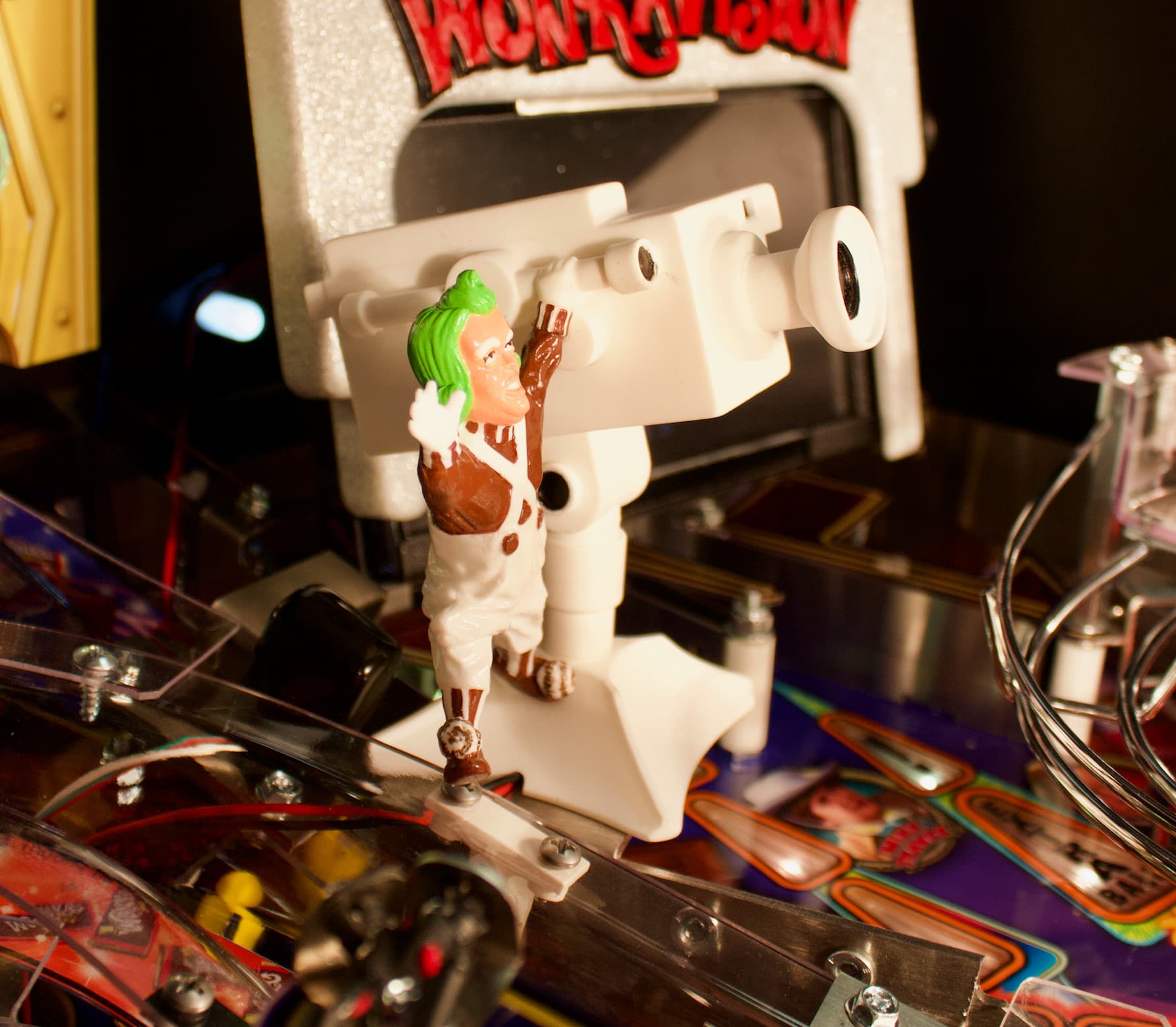 Willy Wonka figurine on pinball machine with green-haired character