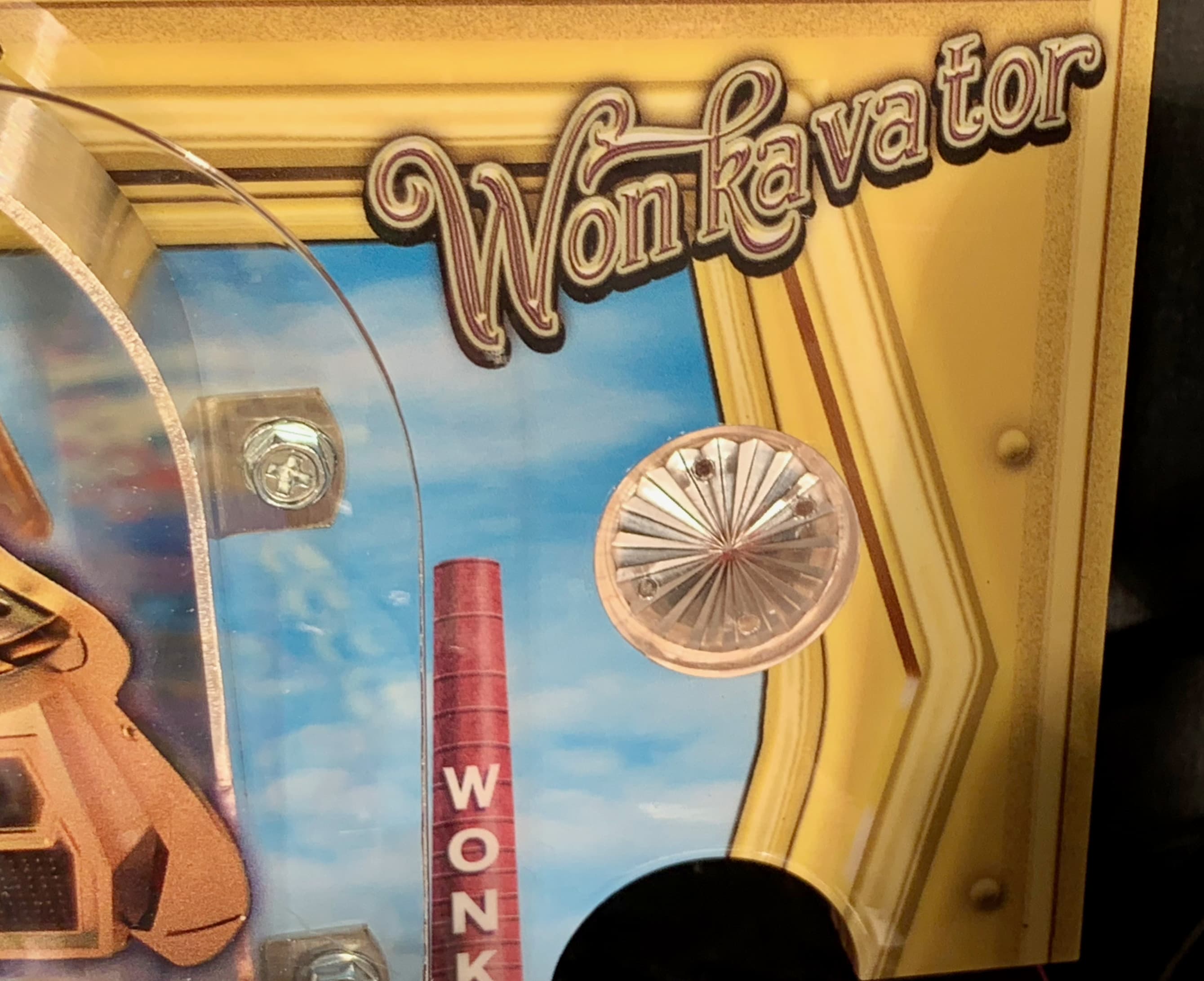 Wonkavator sign with glass tube and red smokestack against yellow background